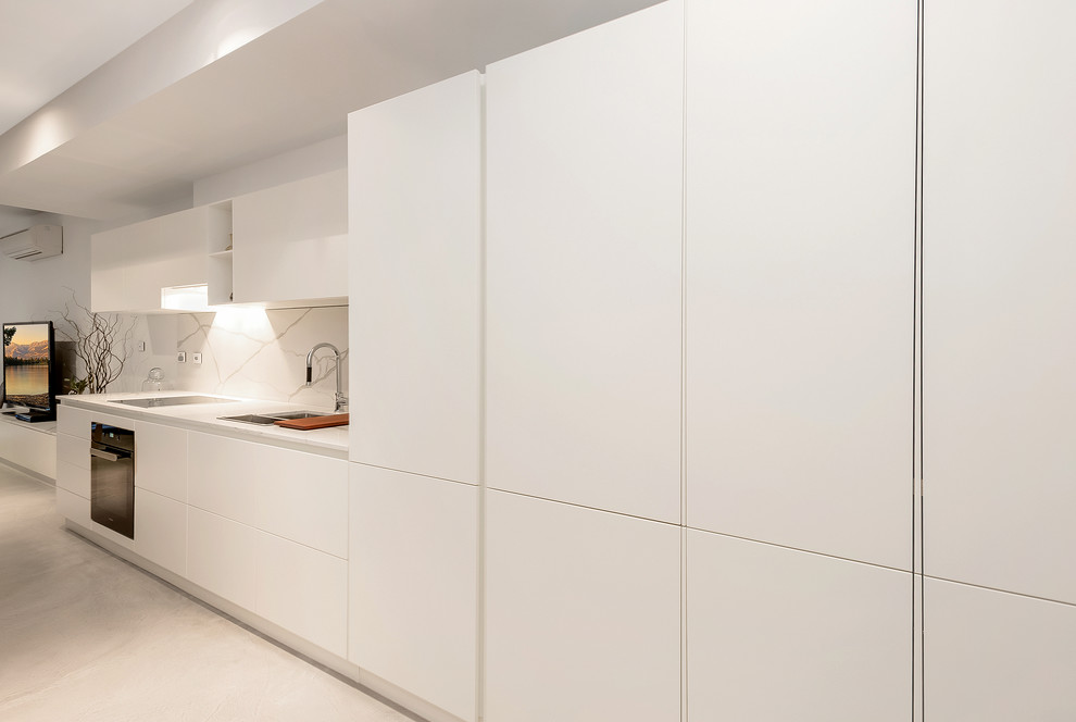 Eat-in kitchen - small modern galley ceramic tile eat-in kitchen idea in Melbourne with a double-bowl sink, raised-panel cabinets, white cabinets, quartz countertops, white backsplash, stone slab backsplash, black appliances and an island