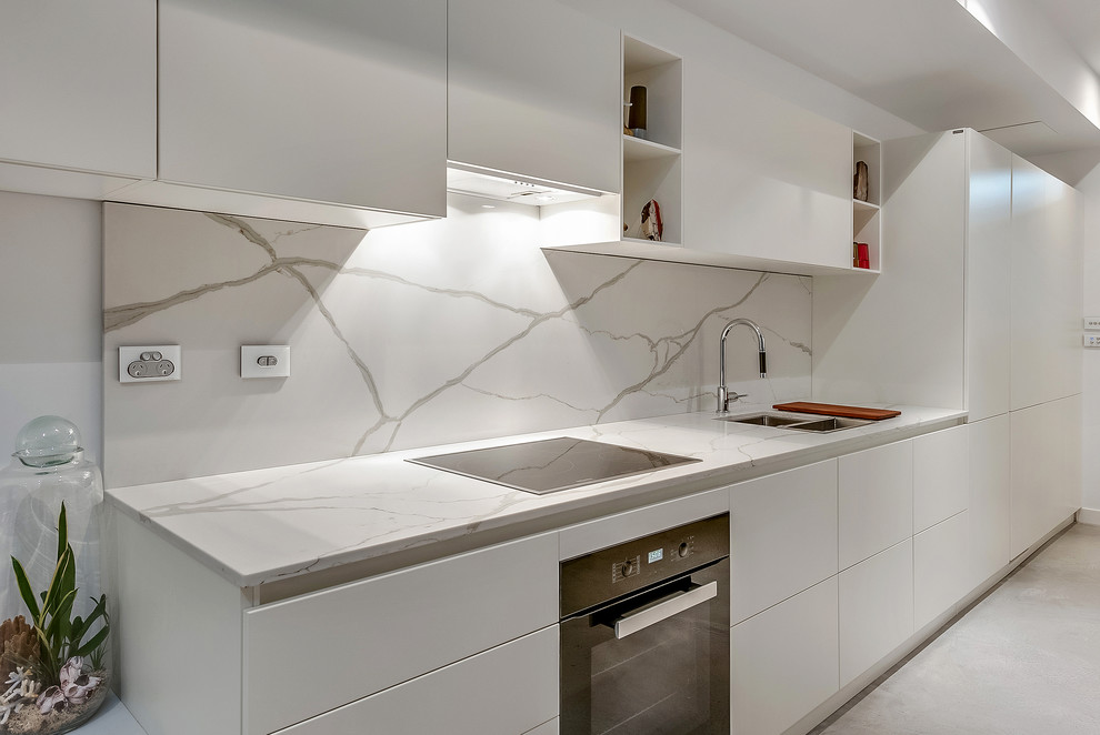 Design ideas for a small modern galley kitchen/diner in Melbourne with a double-bowl sink, raised-panel cabinets, white cabinets, engineered stone countertops, white splashback, stone slab splashback, black appliances, ceramic flooring and an island.