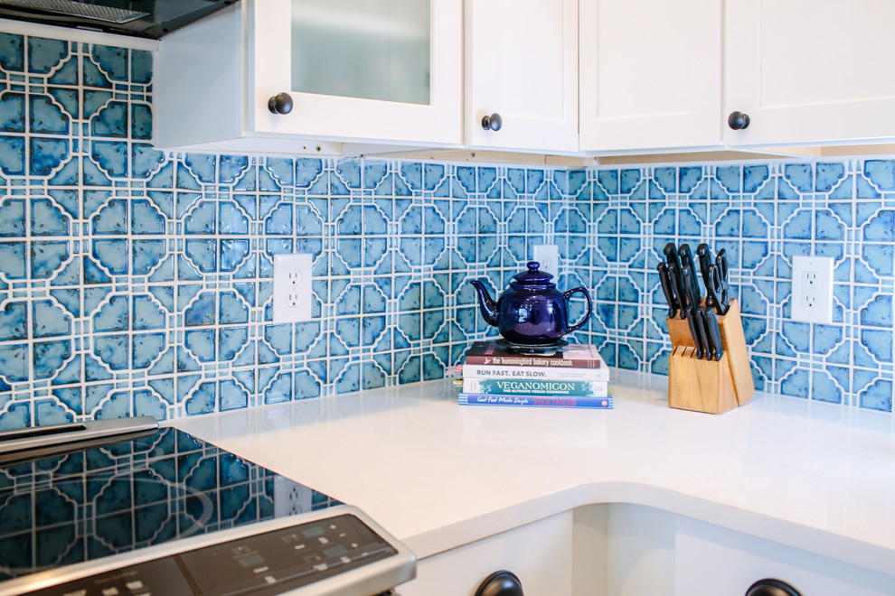 デンバーにあるお手頃価格の小さなエクレクティックスタイルのおしゃれなキッチン (エプロンフロントシンク、シェーカースタイル扉のキャビネット、白いキャビネット、クオーツストーンカウンター、青いキッチンパネル、セラミックタイルのキッチンパネル、シルバーの調理設備、淡色無垢フローリング、茶色い床) の写真