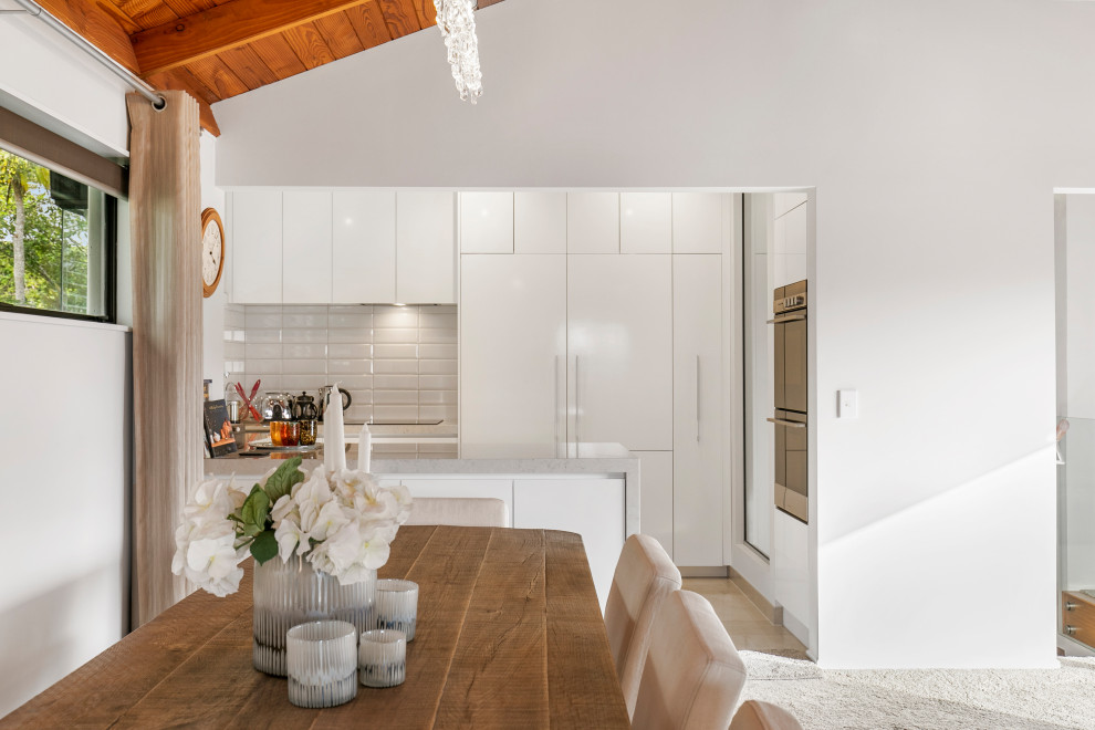 Moderne Küche in U-Form mit Küchenrückwand in Weiß, Rückwand aus Metrofliesen, Porzellan-Bodenfliesen und weißem Boden in Auckland