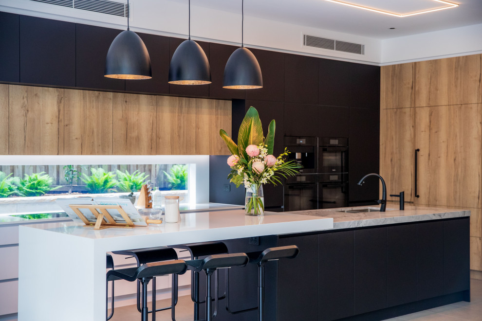 Inspiration for a contemporary l-shaped kitchen in Sydney with a submerged sink, flat-panel cabinets, black cabinets, black appliances, an island, grey floors and white worktops.