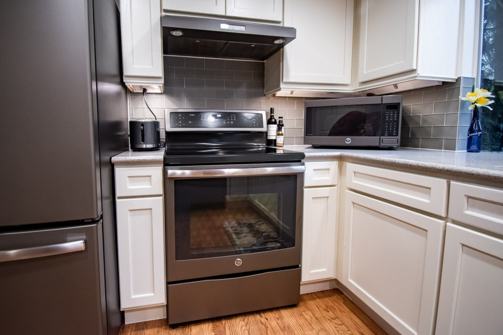 Foto på ett vintage flerfärgad kök, med en undermonterad diskho, skåp i shakerstil, vita skåp, bänkskiva i kvarts, grått stänkskydd, stänkskydd i glaskakel, rostfria vitvaror, mellanmörkt trägolv och en halv köksö