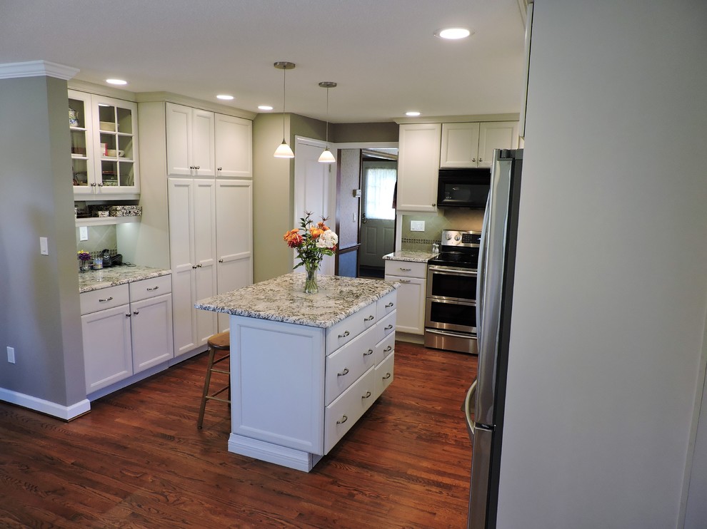 Example of a mid-sized farmhouse galley dark wood floor eat-in kitchen design in New York with an undermount sink, shaker cabinets, white cabinets, granite countertops, green backsplash, porcelain backsplash, stainless steel appliances and an island