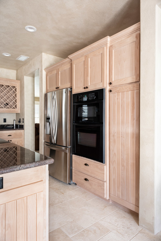 Photo of a medium sized u-shaped kitchen/diner in San Luis Obispo with a built-in sink, recessed-panel cabinets, light wood cabinets, granite worktops, black appliances, limestone flooring, an island, beige floors and black worktops.