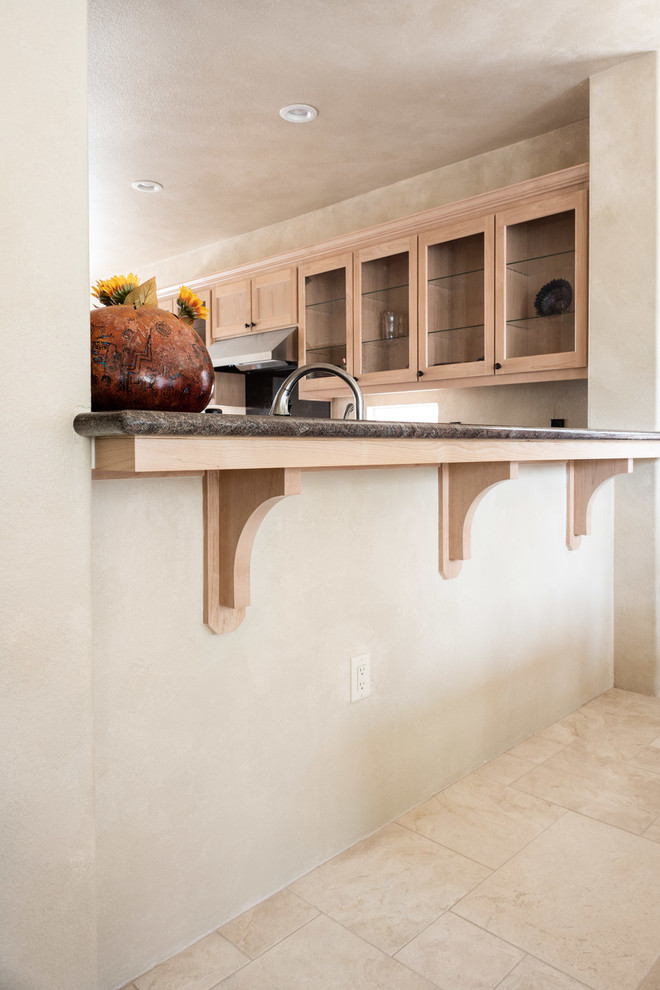 Mid-sized southwest u-shaped limestone floor and beige floor eat-in kitchen photo in San Luis Obispo with a drop-in sink, recessed-panel cabinets, light wood cabinets, granite countertops, black appliances, an island and black countertops
