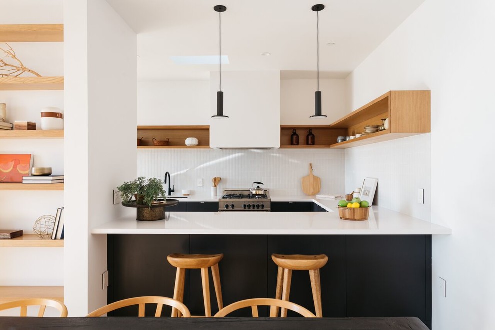 Immagine di una cucina ad U scandinava con lavello sottopiano, nessun'anta, ante in legno chiaro, paraspruzzi bianco e elettrodomestici in acciaio inossidabile