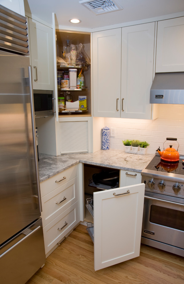 ボストンにある高級な中くらいなトランジショナルスタイルのおしゃれなキッチン (アンダーカウンターシンク、落し込みパネル扉のキャビネット、白いキャビネット、珪岩カウンター、白いキッチンパネル、サブウェイタイルのキッチンパネル、シルバーの調理設備、無垢フローリング、グレーのキッチンカウンター) の写真