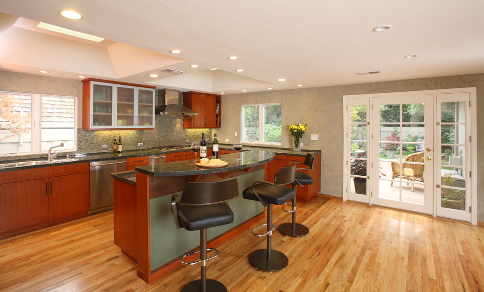 Eat-in kitchen - mid-sized contemporary u-shaped medium tone wood floor and yellow floor eat-in kitchen idea in San Francisco with an undermount sink, flat-panel cabinets, orange cabinets, quartz countertops, green backsplash, glass sheet backsplash, stainless steel appliances, an island and green countertops