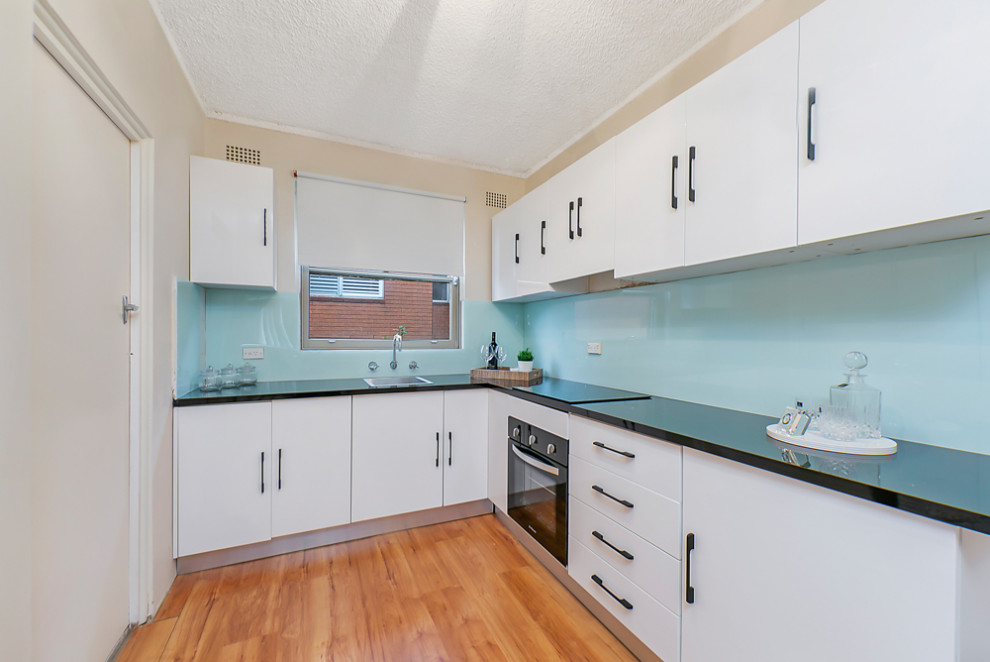 Esempio di una cucina ad ambiente unico design di medie dimensioni con paraspruzzi blu, paraspruzzi con piastrelle in ceramica, pavimento in laminato, pavimento marrone e top nero