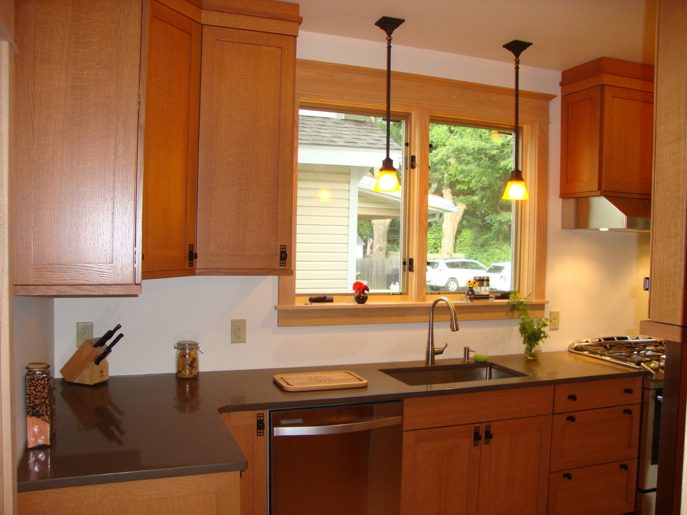 Exempel på ett avskilt, litet amerikanskt l-kök, med en enkel diskho, skåp i shakerstil, skåp i ljust trä, bänkskiva i kvarts, rostfria vitvaror och mellanmörkt trägolv