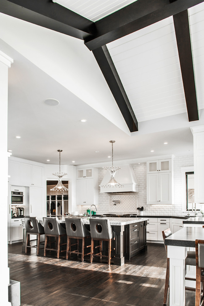 This is an example of a large traditional u-shaped kitchen/diner in Denver with a submerged sink, shaker cabinets, white cabinets, marble worktops, white splashback, metro tiled splashback, stainless steel appliances, dark hardwood flooring and an island.