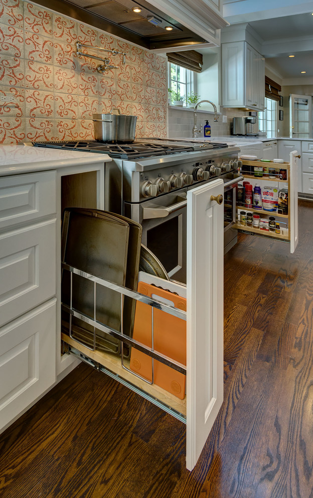 Inspiration for a large transitional u-shaped medium tone wood floor and brown floor eat-in kitchen remodel in Chicago with a farmhouse sink, raised-panel cabinets, white cabinets, quartz countertops, multicolored backsplash, paneled appliances, an island and terra-cotta backsplash