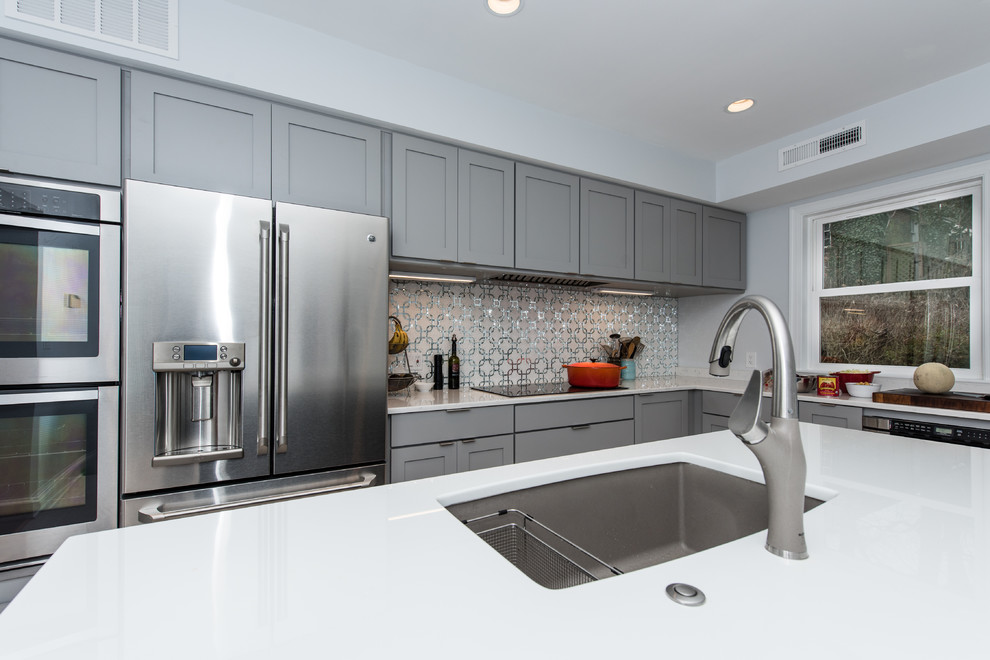 Immagine di una cucina chic di medie dimensioni con lavello sottopiano, ante in stile shaker, ante blu, top in vetro, paraspruzzi grigio, paraspruzzi con piastrelle a mosaico, elettrodomestici in acciaio inossidabile e pavimento in gres porcellanato