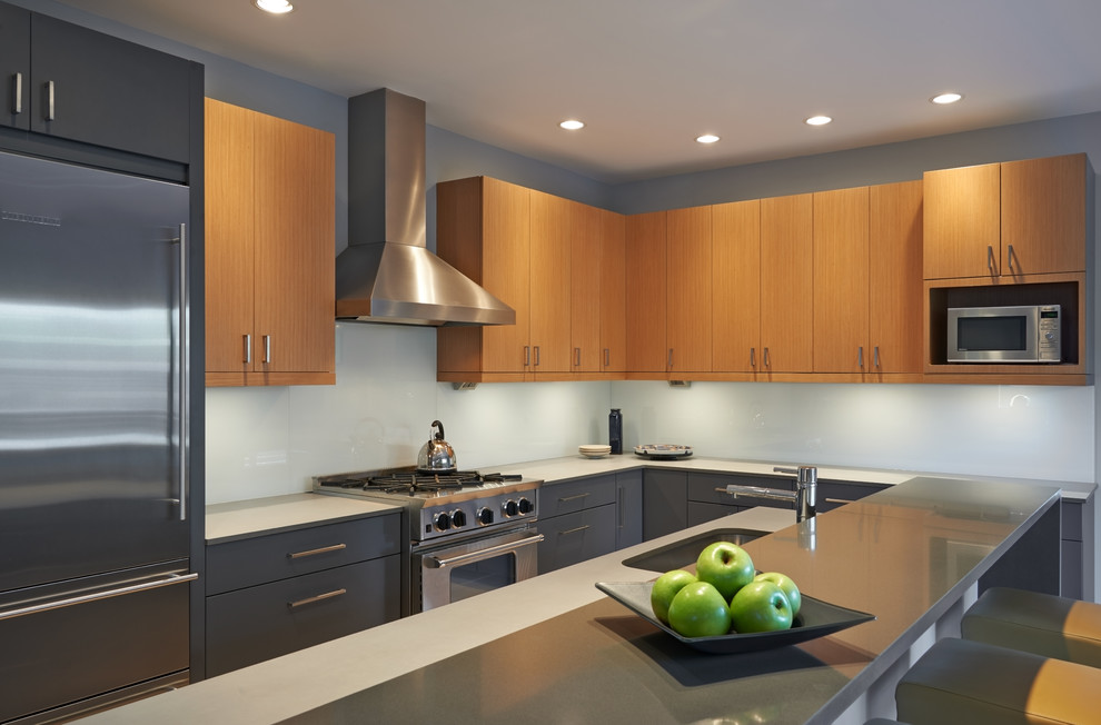 Example of a mid-sized trendy l-shaped bamboo floor open concept kitchen design in Seattle with an island, flat-panel cabinets, light wood cabinets, quartz countertops, blue backsplash, glass sheet backsplash, stainless steel appliances and an undermount sink