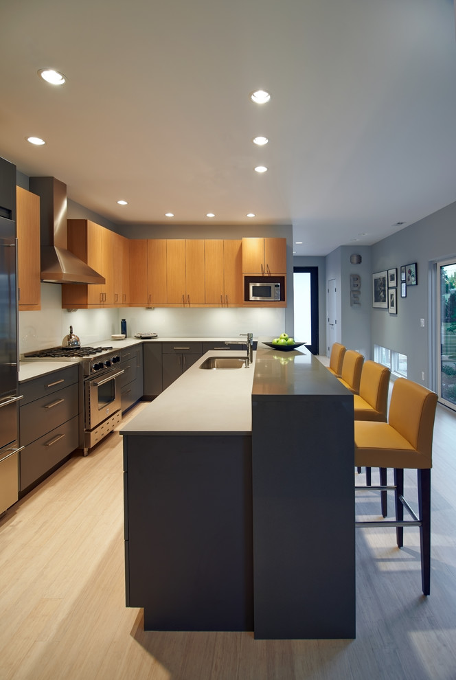 Bild på ett mellanstort funkis kök, med en köksö, släta luckor, bänkskiva i kvarts, rostfria vitvaror, en undermonterad diskho, bambugolv, skåp i ljust trä, blått stänkskydd och glaspanel som stänkskydd