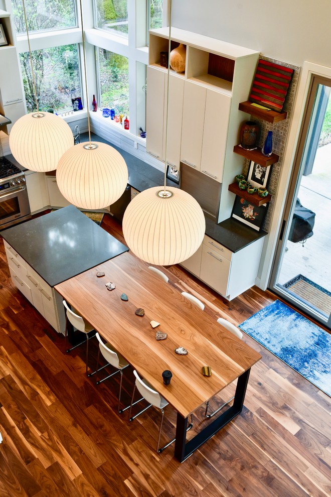 Moderne Küche in U-Form mit Landhausspüle, flächenbündigen Schrankfronten, weißen Schränken, Küchenrückwand in Grau, Rückwand aus Porzellanfliesen, Küchengeräten aus Edelstahl, braunem Holzboden, Kücheninsel, buntem Boden und grauer Arbeitsplatte in Portland
