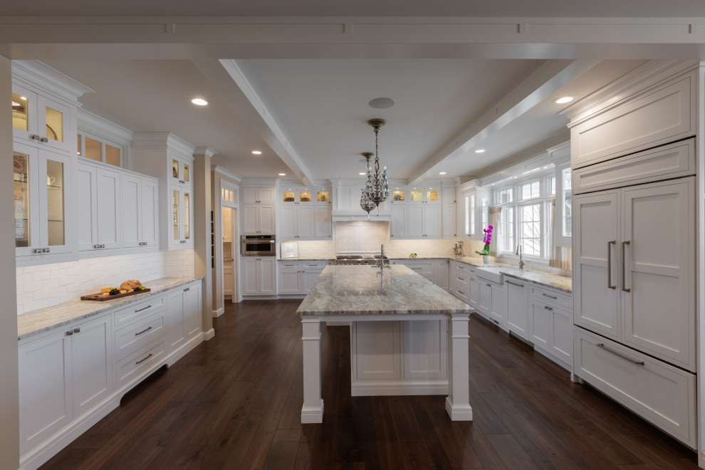 Design ideas for a large classic kitchen/diner in Other with a belfast sink, white cabinets, granite worktops, white splashback, glass tiled splashback, stainless steel appliances, medium hardwood flooring, an island and brown floors.