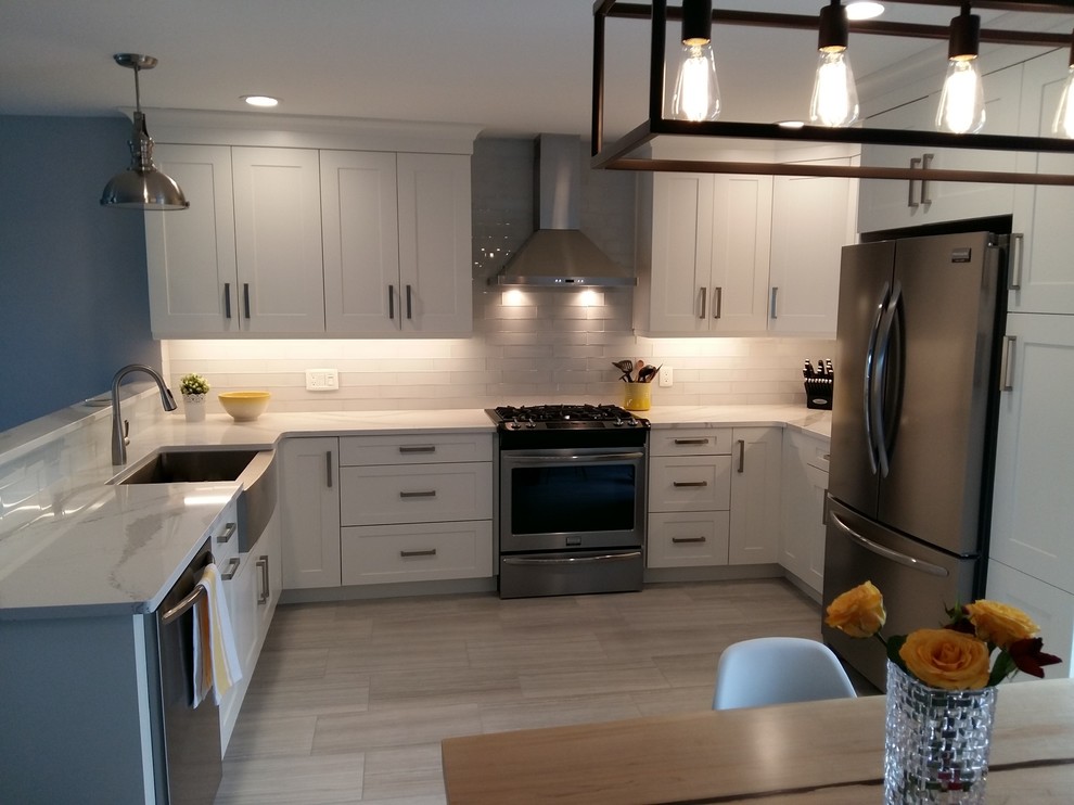 Mid-sized trendy u-shaped porcelain tile eat-in kitchen photo in Toronto with a farmhouse sink, shaker cabinets, white cabinets, quartz countertops, white backsplash, glass tile backsplash and stainless steel appliances