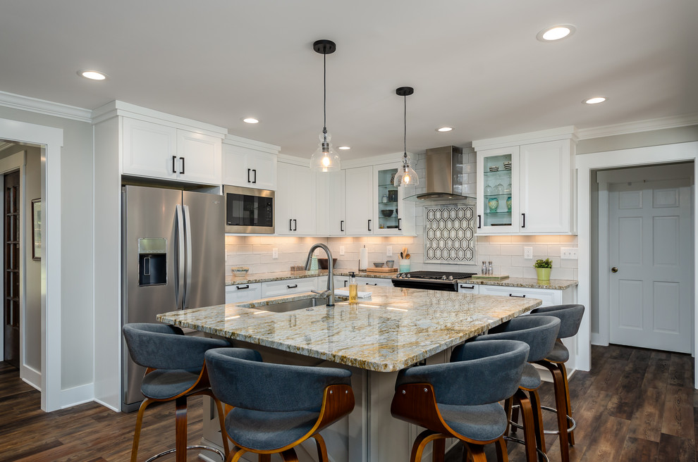 Example of a mid-sized transitional l-shaped medium tone wood floor and brown floor kitchen design in Other with an undermount sink, recessed-panel cabinets, white cabinets, white backsplash, stainless steel appliances, an island and multicolored countertops