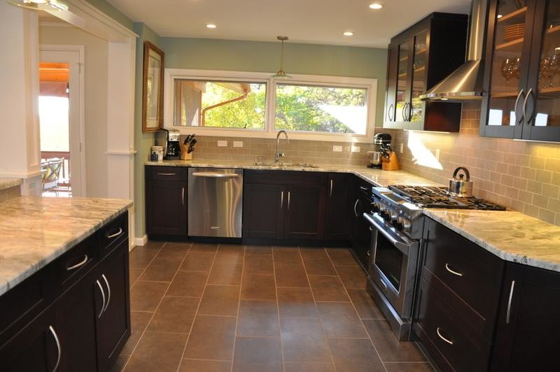 Foto på ett mellanstort funkis kök, med en undermonterad diskho, släta luckor, skåp i mörkt trä, granitbänkskiva, svart stänkskydd, stänkskydd i tunnelbanekakel, rostfria vitvaror och klinkergolv i keramik