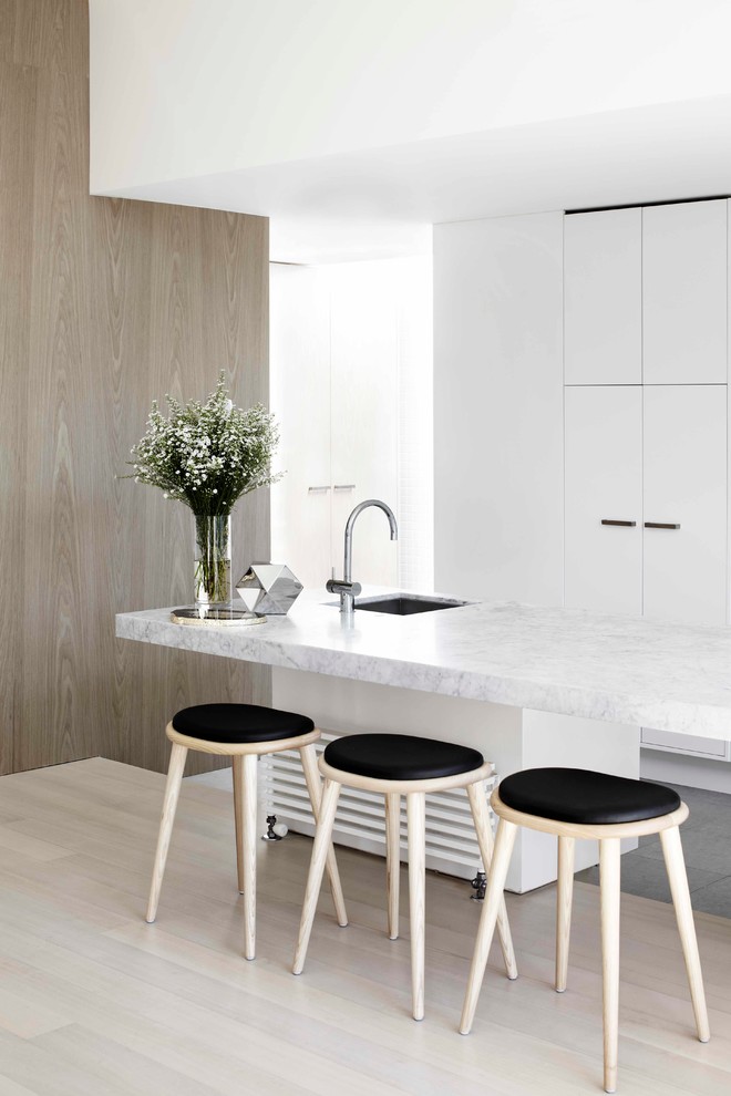 Moderne Küche mit Unterbauwaschbecken, flächenbündigen Schrankfronten, weißen Schränken, hellem Holzboden und Kücheninsel in Melbourne