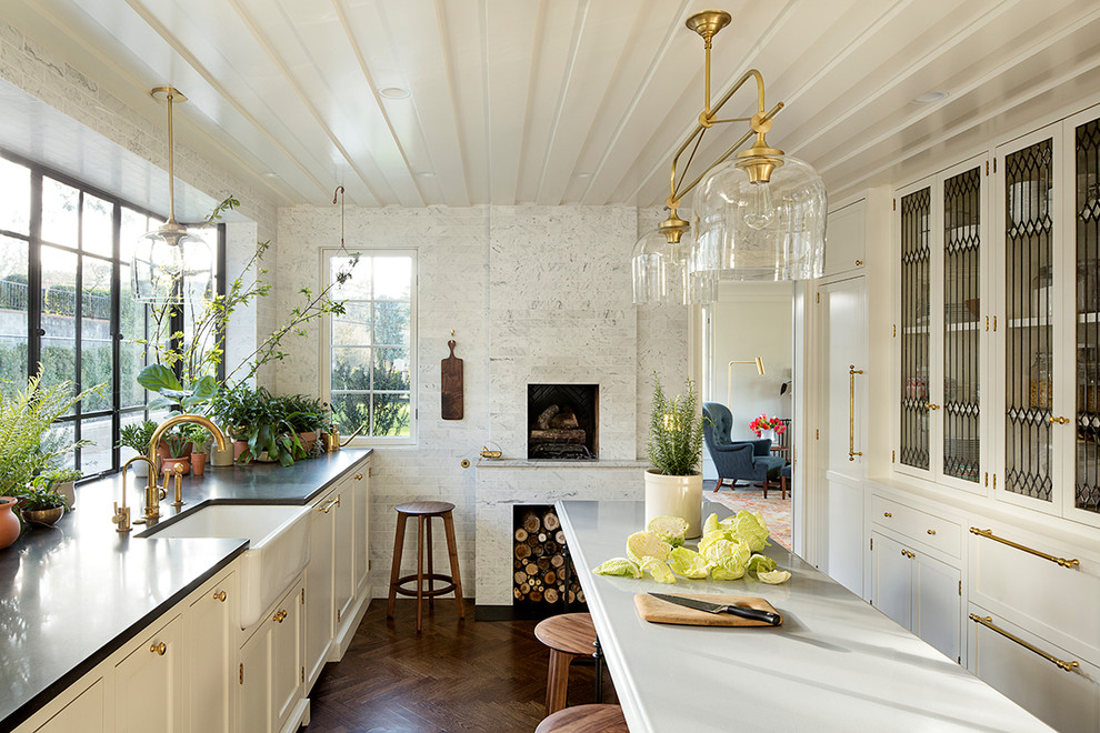 Foto de cocina clásica con fregadero sobremueble, armarios tipo vitrina, puertas de armario blancas, salpicadero de vidrio, suelo de madera oscura y una isla
