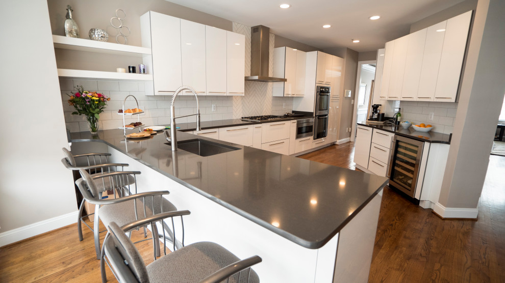 Idéer för att renovera ett mellanstort funkis grå grått kök, med en undermonterad diskho, släta luckor, vita skåp, bänkskiva i kvarts, vitt stänkskydd, stänkskydd i keramik, rostfria vitvaror, mellanmörkt trägolv, en halv köksö och brunt golv