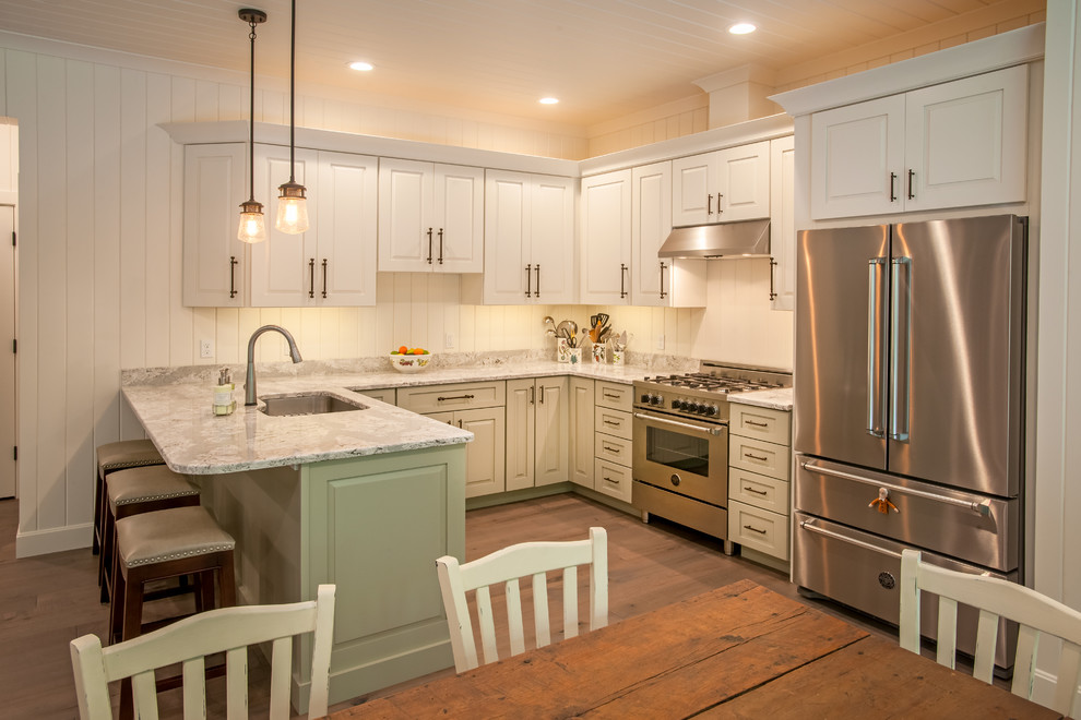 Example of a mid-sized country u-shaped medium tone wood floor and gray floor eat-in kitchen design in Other with an undermount sink, raised-panel cabinets, white cabinets, quartz countertops, white backsplash, wood backsplash, stainless steel appliances, a peninsula and white countertops