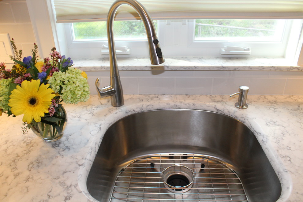 Imagen de cocina comedor clásica de tamaño medio sin isla con fregadero de un seno, armarios estilo shaker, puertas de armario blancas, encimera de cuarzo compacto, salpicadero blanco, salpicadero de azulejos tipo metro, electrodomésticos de acero inoxidable, suelo de madera en tonos medios y suelo marrón