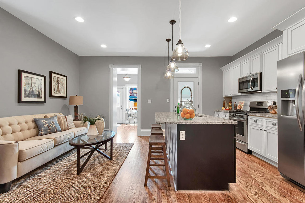 Mid-sized transitional galley dark wood floor and brown floor open concept kitchen photo in St Louis with an undermount sink, recessed-panel cabinets, white cabinets, granite countertops, white backsplash, subway tile backsplash, stainless steel appliances and an island