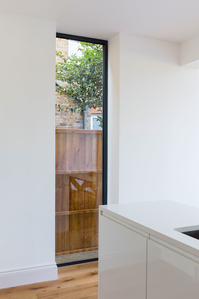 Foto di una grande cucina contemporanea con ante lisce, ante bianche, top in quarzite, elettrodomestici da incasso e pavimento in legno massello medio
