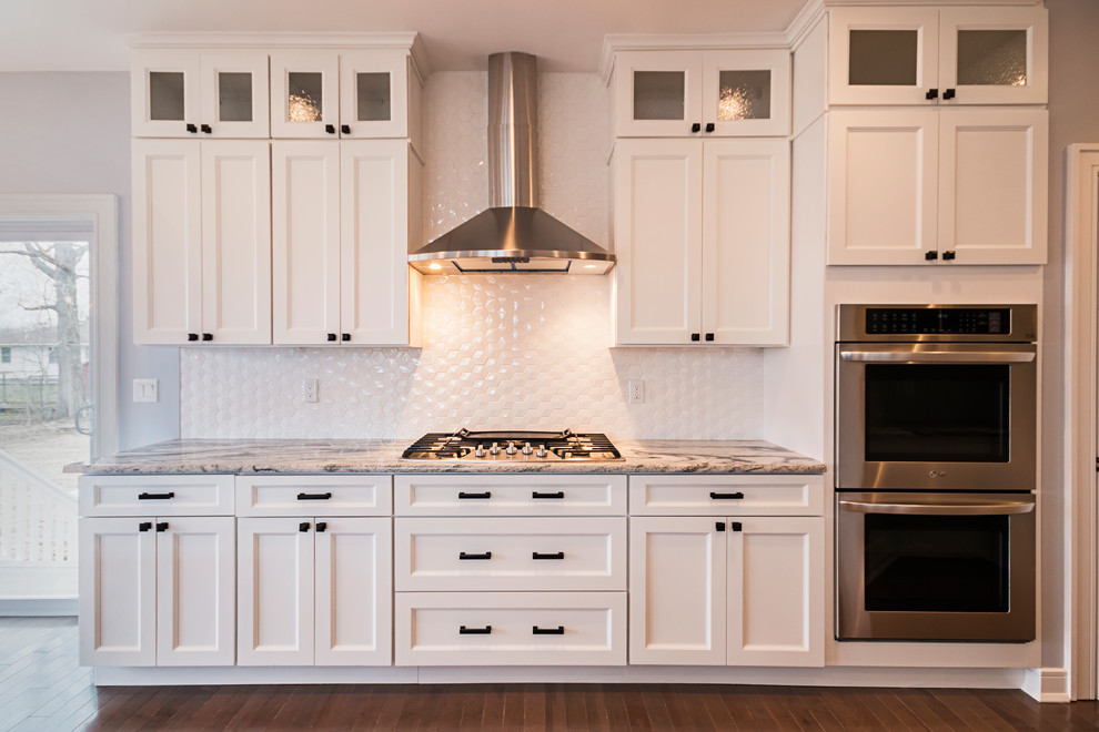 Amerikansk inredning av ett mellanstort flerfärgad flerfärgat kök, med en undermonterad diskho, skåp i shakerstil, vita skåp, vitt stänkskydd, laminatgolv, en halv köksö, brunt golv, stänkskydd i keramik och rostfria vitvaror