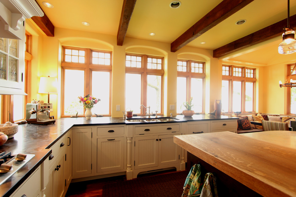 Bild på ett stort lantligt kök, med en trippel diskho, luckor med profilerade fronter, vita skåp, granitbänkskiva, flerfärgad stänkskydd, stänkskydd i stenkakel, integrerade vitvaror, en köksö och mellanmörkt trägolv