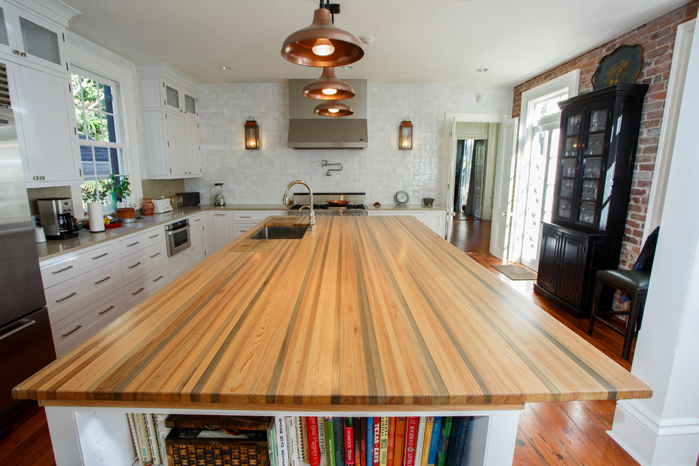 Immagine di una grande cucina minimal con lavello sottopiano, ante a filo, ante bianche, top in legno, elettrodomestici in acciaio inossidabile, parquet scuro, pavimento marrone e top verde