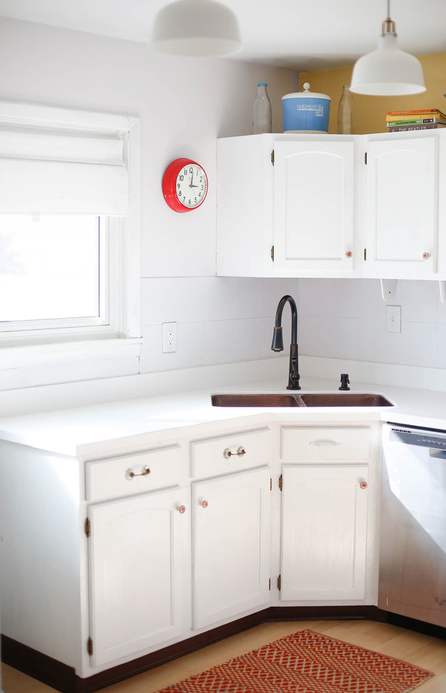 Diseño de cocina minimalista de tamaño medio con fregadero bajoencimera, puertas de armario blancas, encimera de acrílico, salpicadero blanco y suelo de madera clara