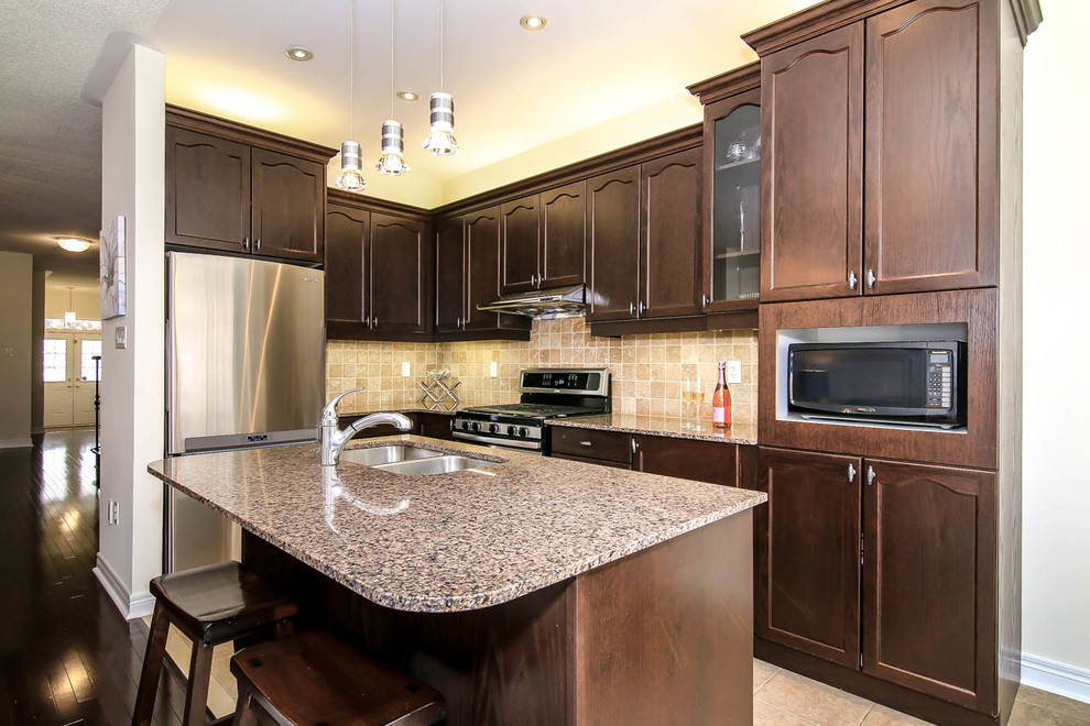 Mid-sized trendy l-shaped ceramic tile eat-in kitchen photo in Toronto with an undermount sink, recessed-panel cabinets, medium tone wood cabinets, granite countertops, beige backsplash, ceramic backsplash, stainless steel appliances and an island
