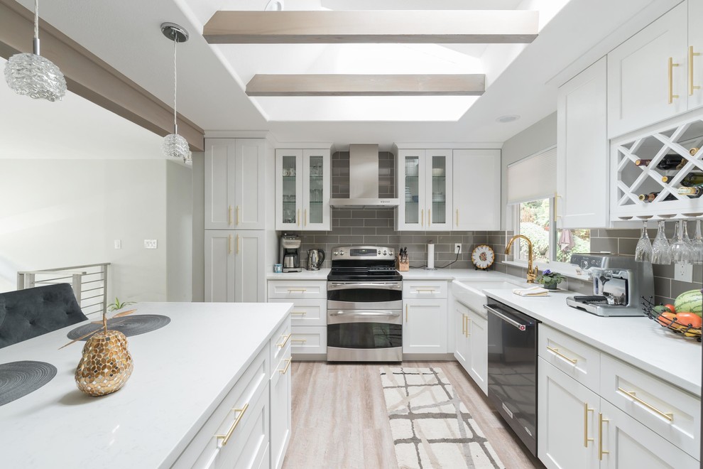 Inspiration for a mid-sized transitional l-shaped vinyl floor and gray floor eat-in kitchen remodel in Seattle with a farmhouse sink, shaker cabinets, white cabinets, quartz countertops, gray backsplash, ceramic backsplash, stainless steel appliances and an island