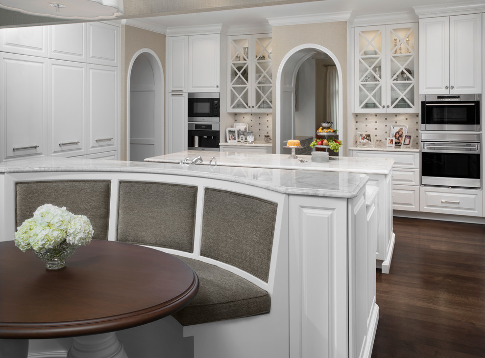 Kitchen pantry - large traditional dark wood floor kitchen pantry idea in Detroit with an undermount sink, raised-panel cabinets, white cabinets, quartzite countertops, white backsplash, ceramic backsplash, stainless steel appliances and two islands