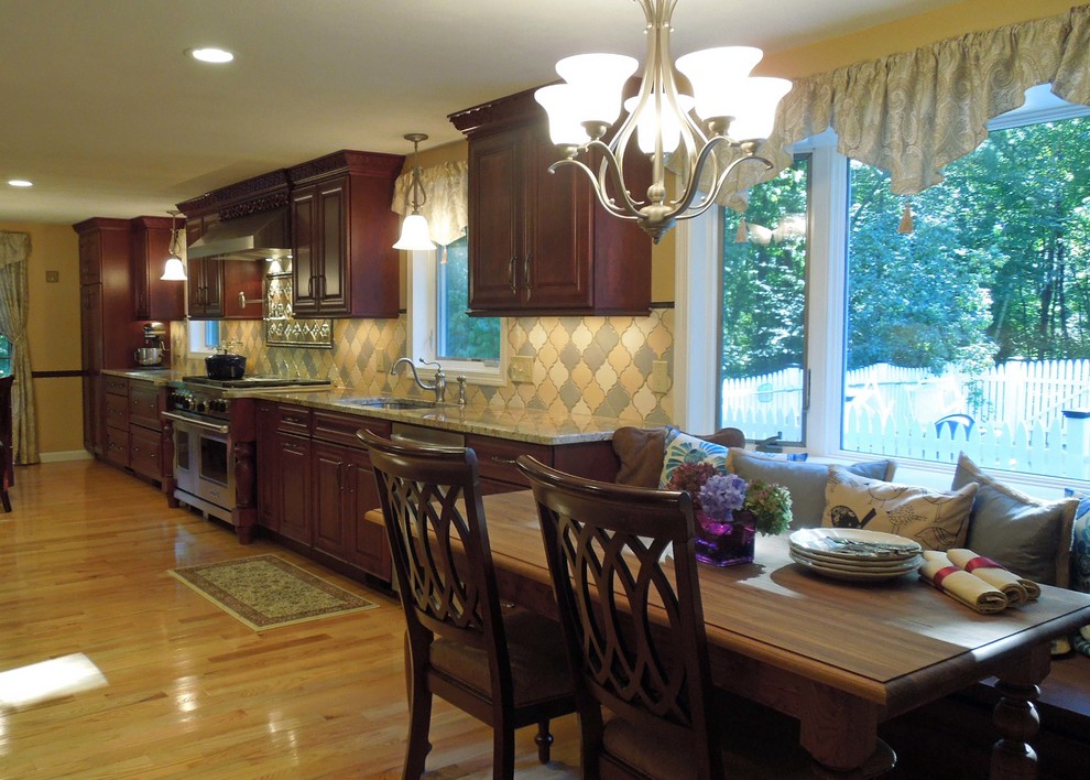 Exempel på ett klassiskt kök, med en undermonterad diskho, luckor med upphöjd panel, skåp i mörkt trä, granitbänkskiva, flerfärgad stänkskydd och rostfria vitvaror