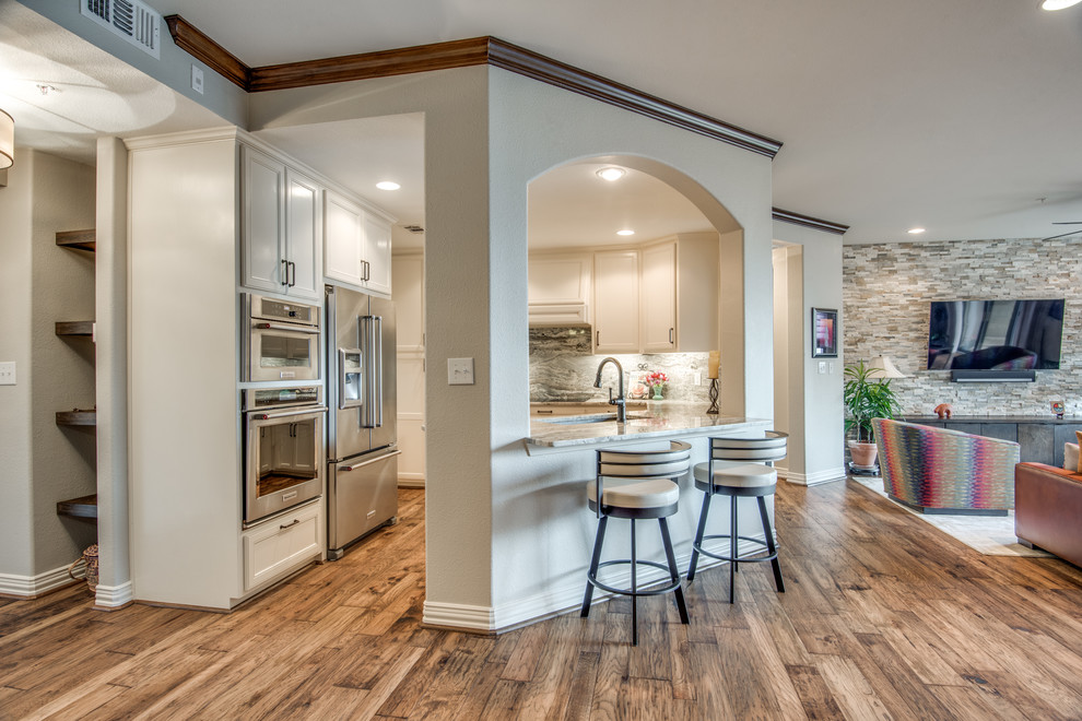 Example of a mid-sized southwest u-shaped medium tone wood floor and brown floor kitchen design in Dallas with an undermount sink, beaded inset cabinets, white cabinets, granite countertops, green backsplash, stone slab backsplash, stainless steel appliances and gray countertops