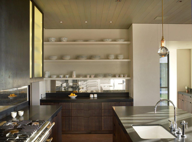 Immagine di una cucina parallela minimal con lavello sottopiano, ante lisce, ante in legno scuro, top in granito e elettrodomestici in acciaio inossidabile