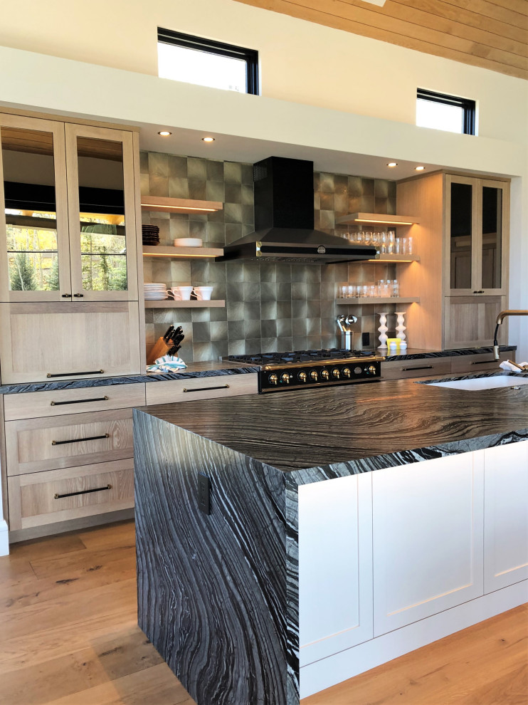 Inspiration for a medium sized contemporary galley open plan kitchen in Other with a single-bowl sink, shaker cabinets, light wood cabinets, metallic splashback, black appliances, medium hardwood flooring, an island, brown floors, black worktops and a wood ceiling.