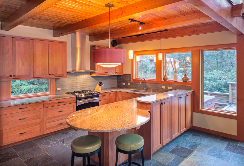 Amerikansk inredning av ett mellanstort kök, med en undermonterad diskho, skåp i shakerstil, skåp i ljust trä, granitbänkskiva, grått stänkskydd, stänkskydd i glaskakel, rostfria vitvaror, skiffergolv, en halv köksö och svart golv