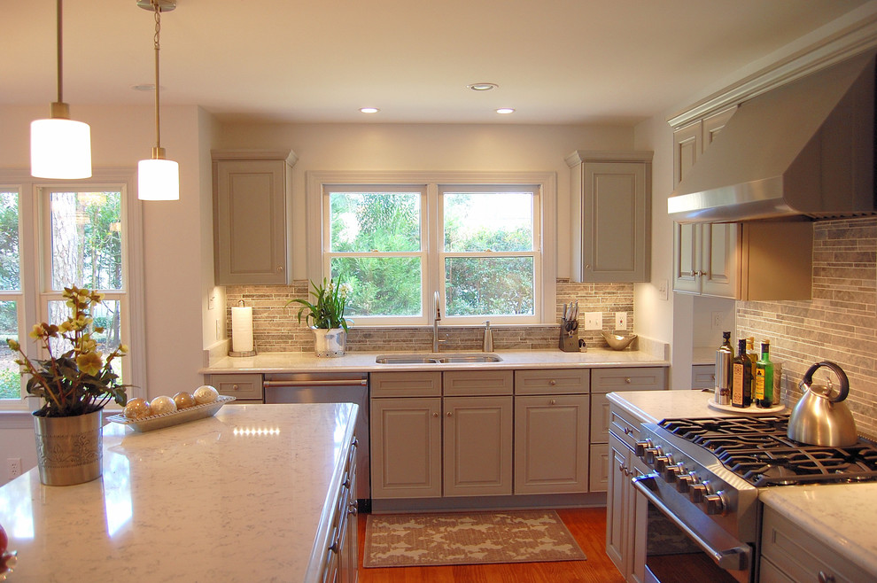Photo of a large classic kitchen in Atlanta with grey cabinets, engineered stone countertops, grey splashback, stone tiled splashback, stainless steel appliances, medium hardwood flooring, an island, a submerged sink and raised-panel cabinets.
