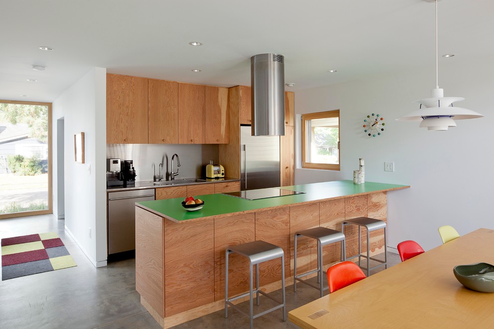 Пример оригинального дизайна: параллельная кухня-гостиная в современном стиле с плоскими фасадами, фасадами цвета дерева среднего тона, фартуком цвета металлик, фартуком из металлической плитки, техникой из нержавеющей стали, бетонным полом и зеленой столешницей
