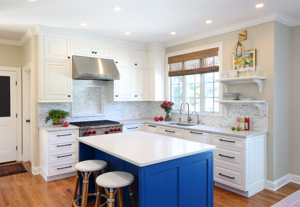 Exempel på ett klassiskt l-kök, med en undermonterad diskho, vita skåp, bänkskiva i kvarts, vitt stänkskydd, stänkskydd i marmor, rostfria vitvaror, mellanmörkt trägolv, en köksö och luckor med upphöjd panel