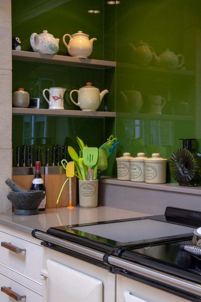 Foto på ett mycket stort vintage grå kök och matrum, med en rustik diskho, skåp i shakerstil, gula skåp, granitbänkskiva, grönt stänkskydd, glaspanel som stänkskydd, integrerade vitvaror, klinkergolv i keramik, en köksö och flerfärgat golv