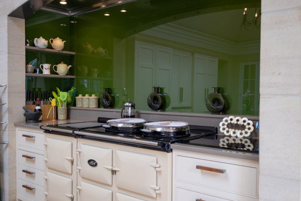 Foto på ett mycket stort vintage grå kök och matrum, med en rustik diskho, skåp i shakerstil, gula skåp, granitbänkskiva, grönt stänkskydd, glaspanel som stänkskydd, integrerade vitvaror, klinkergolv i keramik, en köksö och flerfärgat golv