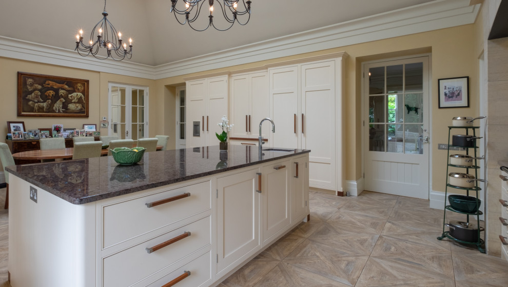 Inspiration for an expansive classic kitchen/diner in Hampshire with a belfast sink, shaker cabinets, yellow cabinets, granite worktops, green splashback, glass sheet splashback, integrated appliances, ceramic flooring, an island, multi-coloured floors and grey worktops.
