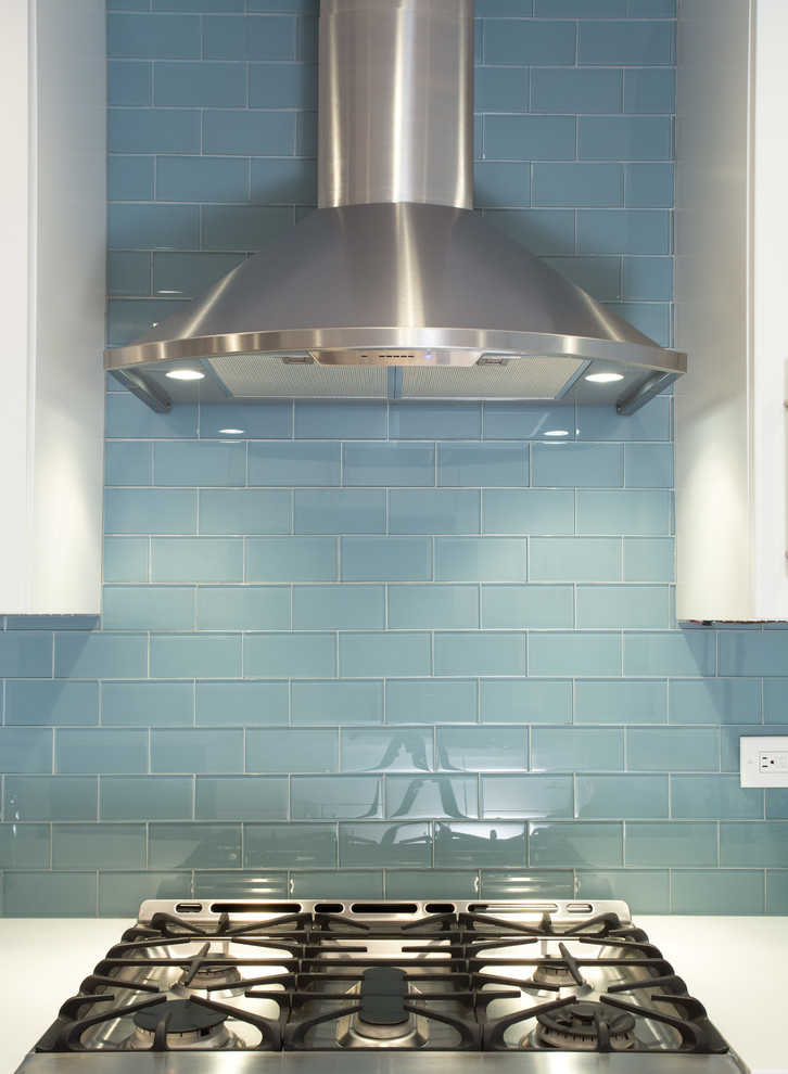 Bild på ett mellanstort funkis kök, med en undermonterad diskho, släta luckor, vita skåp, blått stänkskydd, stänkskydd i tunnelbanekakel, rostfria vitvaror, mellanmörkt trägolv och bänkskiva i kvarts